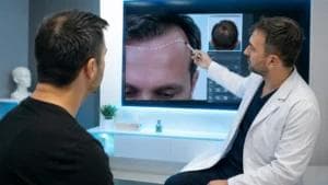 İkinci saç ekimi planlaması için modern bir saç ekimi kliniğinde doktorun dijital saç analizi ekranında hastanın saç çizgisini ve donör bölgesini değerlendirerek revizyon operasyonunu planladığı profesyonel konsültasyon sahnesi.